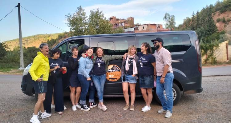 Group of people posing in front of a tour van with 'Morocco Trails' logo.