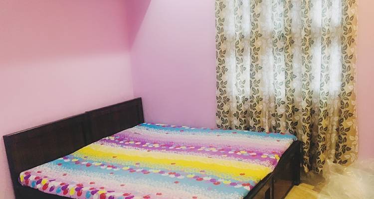 Innenraum eines Schlafzimmers mit rosa Wänden und einem Fenstervorhang.