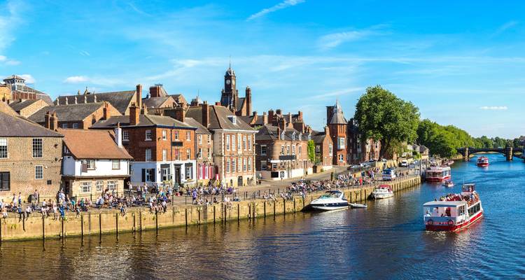 View of York riverside with historic buildings and pedestrians in England.