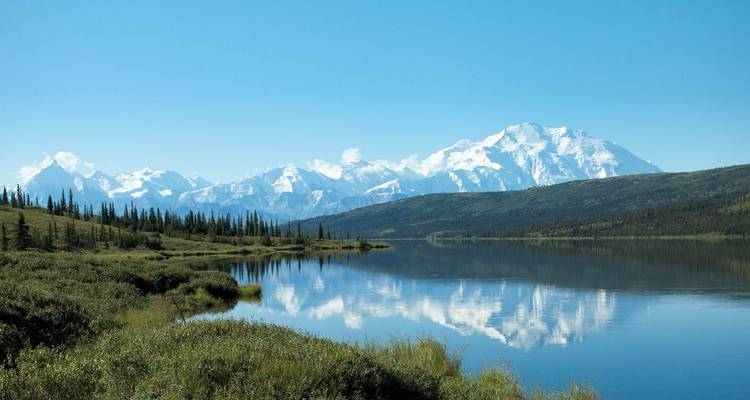Le Denali enneigé se reflétant parfaitement dans un lac tranquille d'Alaska par une journée claire.