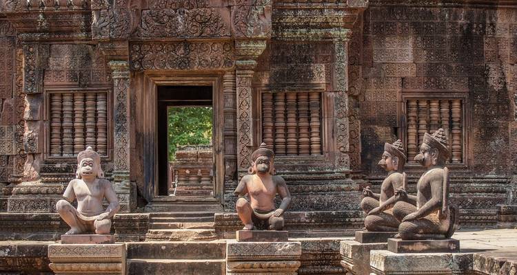Oude stenen sculpturen bij een tempel met ingewikkelde houtsnijwerk.

Wait, let me correct that - "carvings" in stone would be "gravures" or "beeldhouwwerk", not "houtsnijwerk" (which is woodcarving).

Oude stenen sculpturen bij een tempel met ingewikkelde gravures.