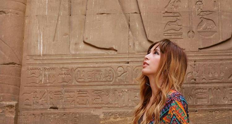 Frau bewundert altägyptische Hieroglyphen an einer Wand