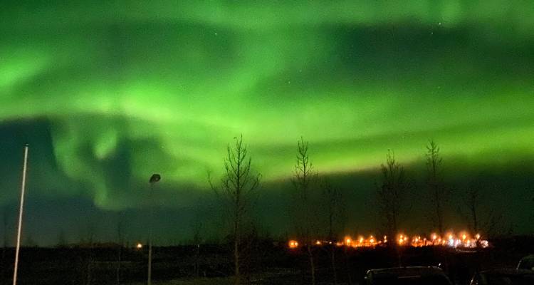 Aurores boréales brillant dans le ciel nocturne au-dessus d'une ville.