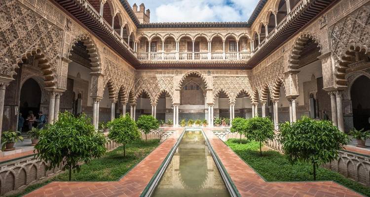 Een ingewikkelde binnenplaats met weelderig groen en symmetrische bogen.