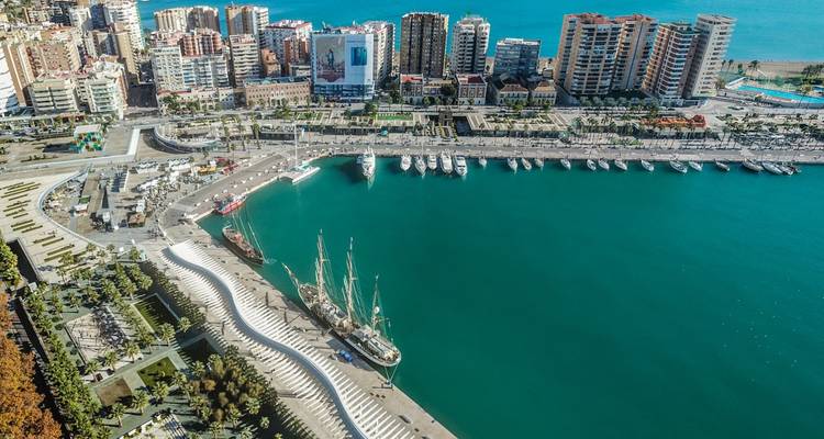 Küstenansicht von Málaga mit einem Yachthafen und dicht bebauter Stadtlandschaft.
