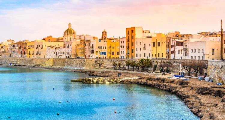 Eine Küstenstadt mit bunten Gebäuden, die sich in der ruhigen See spiegeln.