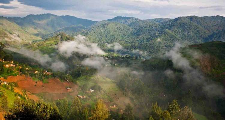 Collines couvertes de brume avec des villages éparpillés dans une vallée.