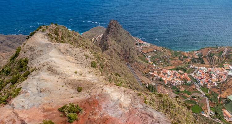 Aerial view of a coastal town with red rooftops and cliffs.
