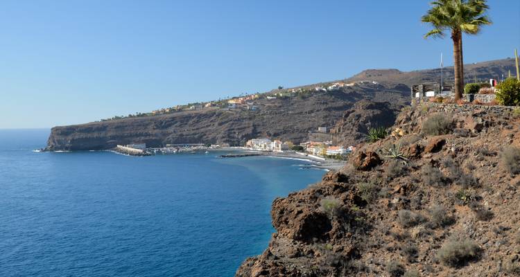Coastal view with a small town on a cliff and blue ocean.