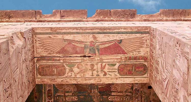 Oud-Egyptische tempel met gebeeldhouwde reliëfs en een gevleugeld zonneschijfsymbool.