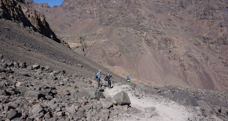 Excursionistas en un sendero rocoso en una región montañosa.