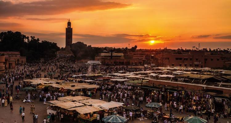 Una plaza de mercado bulliciosa al atardecer en Marrakech.