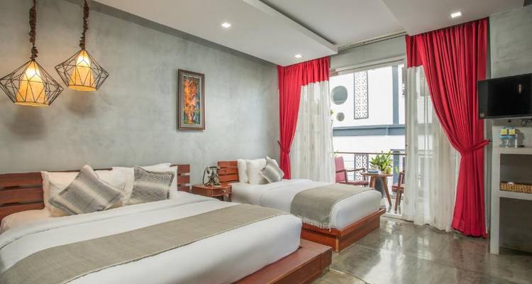 Hotel room with two beds and red curtains.