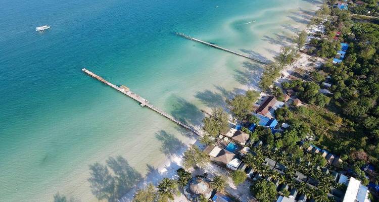Aerial view of a beach with piers and turquoise water.