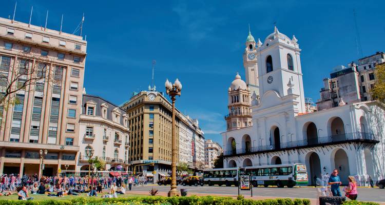 Place de ville animée avec bâtiments historiques et activité bouillonnante.