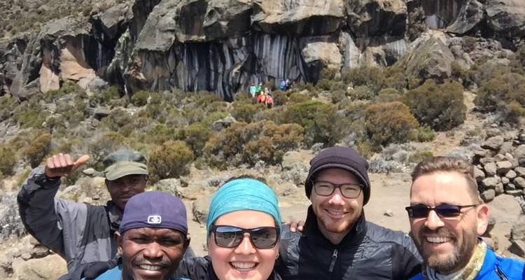 Groep wandelaars poserend voor rotsachtig terrein.