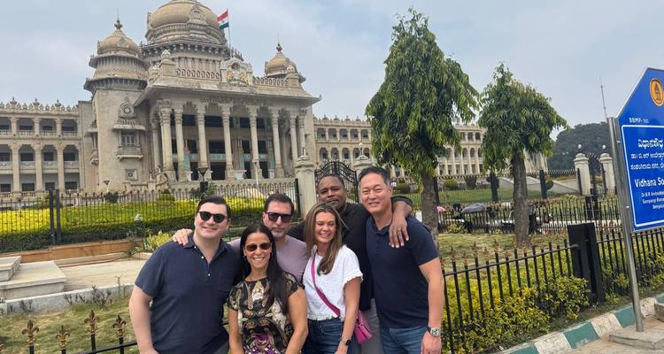 Grupo de personas posando frente a un gran edificio gubernamental ornamentado.
