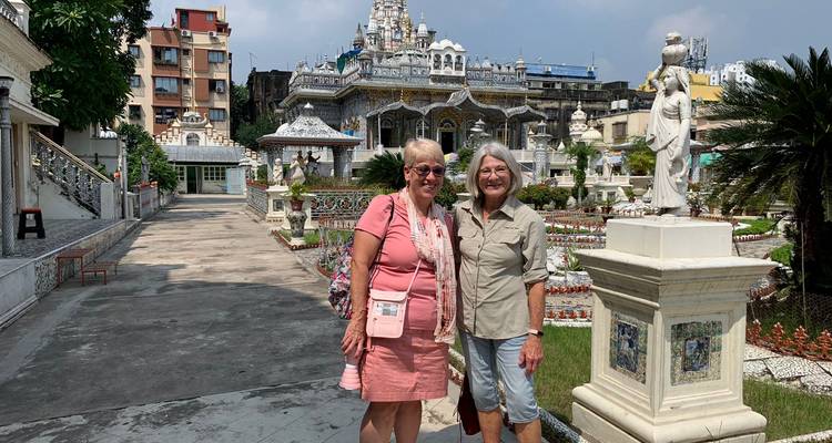 Dos personas de pie frente a una estructura de templo detallada.