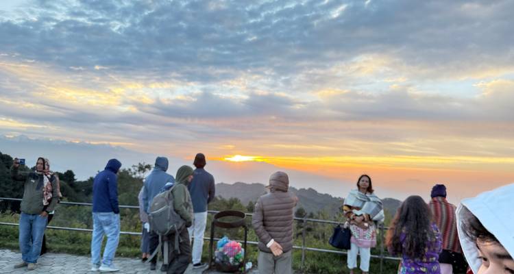 Groupe de personnes observant un lever de soleil depuis un point de vue.