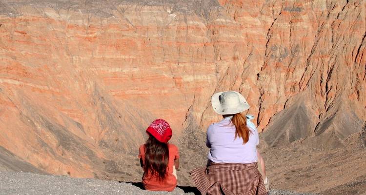 Twee mensen die aan de rand van een canyon zitten met gelaagde rotsformaties.