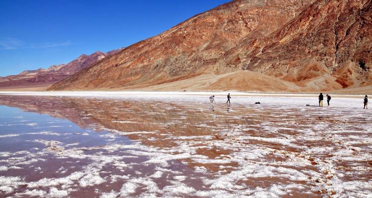 Menschen die een reflecterende zoutvlakte verkennen met bergen op de achtergrond.