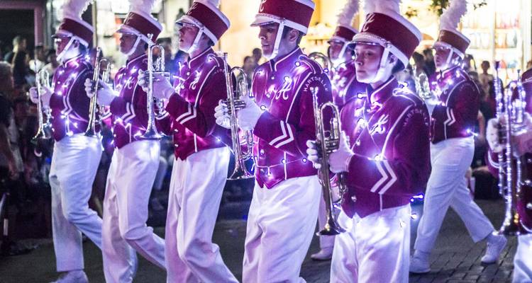 Illuminated marching band in a parade at night.