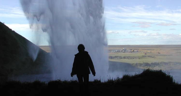 Person silhouetted by a powerful waterfall in Iceland.