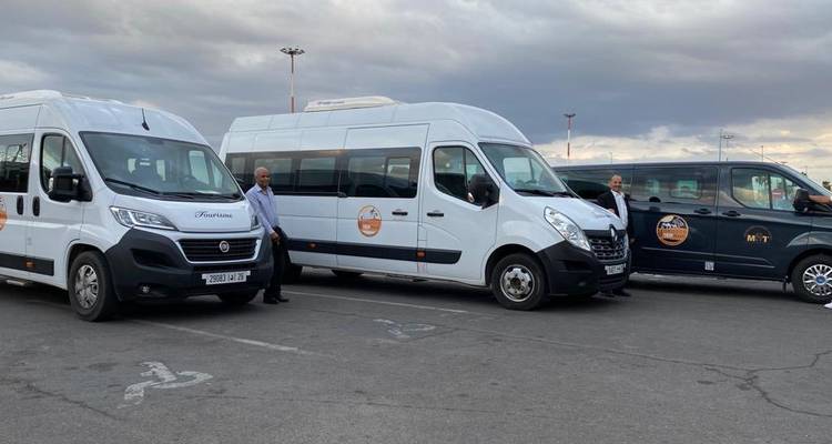 Een groep witte bestelwagens geparkeerd, met mensen die er in de buurt staan.
