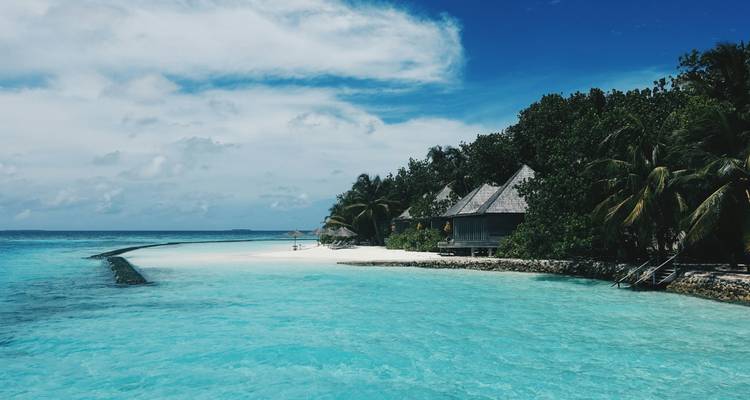 Aguas cristalinas con playa y villas con exuberante vegetación.