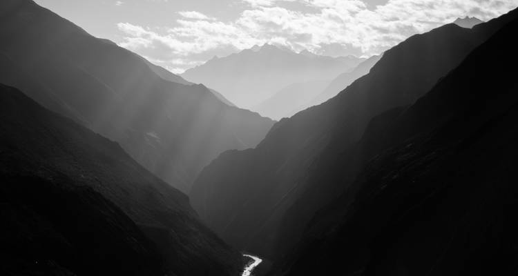 Black and white photograph of a valley with light beams.