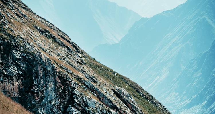 Mountain side with grass and rocks in a blue hue.