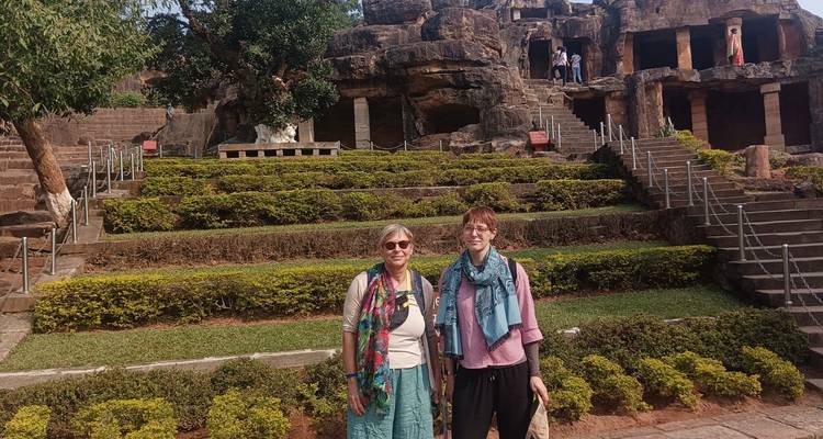 Zwei Touristen lächeln bei antiken Höhlen.