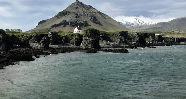 Een schilderachtig uitzicht op een berg met een wit gebouw naast de zee.