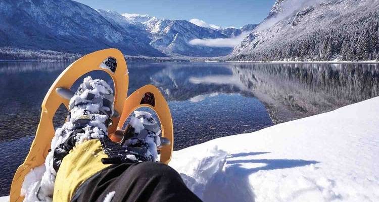 Montagnes enneigées et une paire de raquettes près d'un lac.