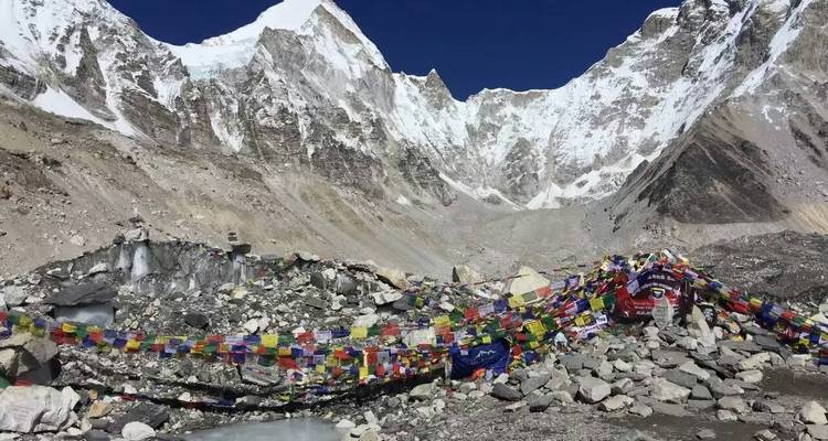 Prayer flags and rocky terrain at the base of towering mountains.