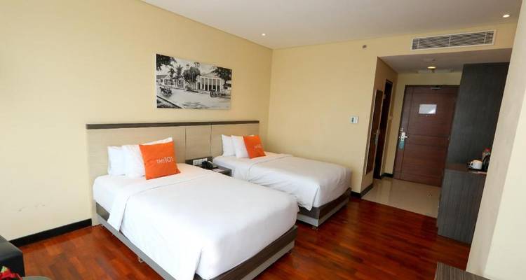 Hotel room with two beds and wooden flooring.