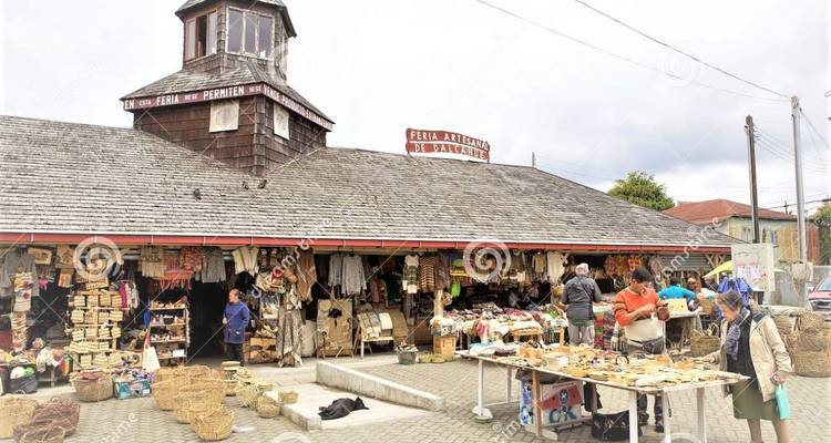 Outdoor marketplace with various stalls and people browsing.