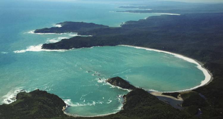 Aerial view of a crescent-shaped beach with turquoise waters.