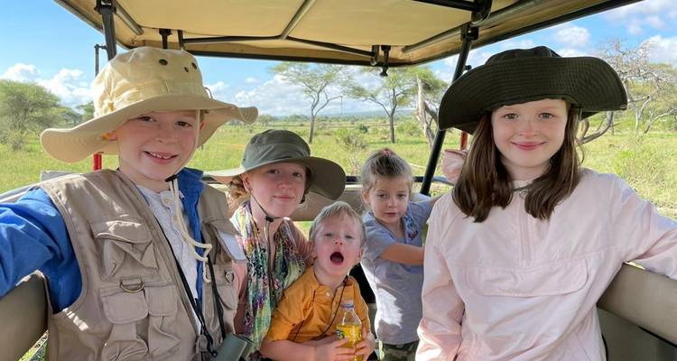 Kinder lächeln in einem Safari-Fahrzeug während einer Pirschfahrt in Tansania.