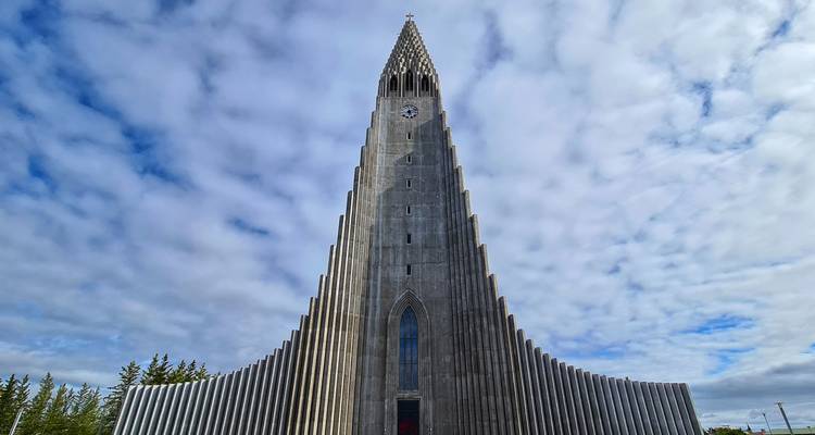 Grande église de pierre avec un clocher saisissant sur un ciel bleu.