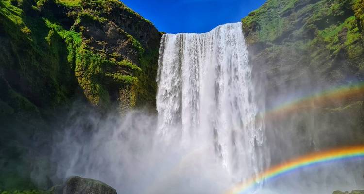 Grande cascade avec un arc-en-ciel dans un cadre verdoyant luxuriant.