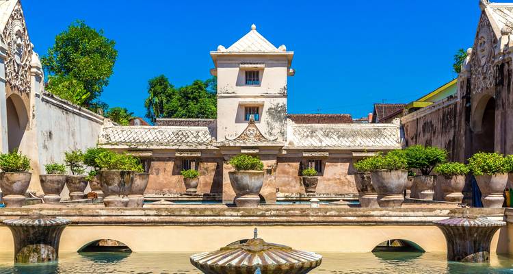 Historic Taman Sari Water Castle courtyard with decorative urns, pools, and bright blue sky.