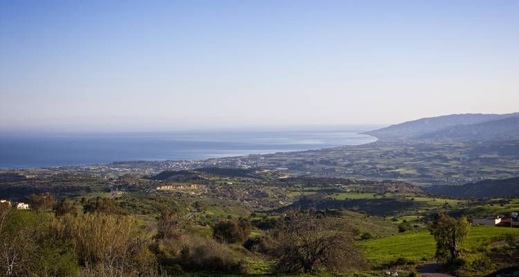 Expansive view of green fields and hills leading to the sea.