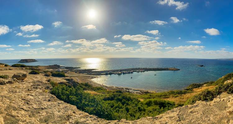 A stunning coastal view with the sun peeking through the clouds.