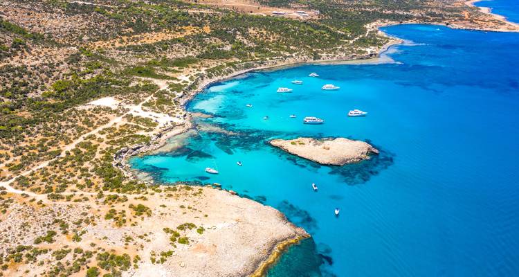 Aerial view of turquoise waters with small islands and boats.