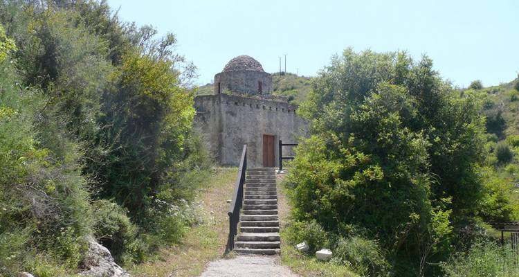 Vieux bâtiment en pierre avec un escalier entouré de verdure.