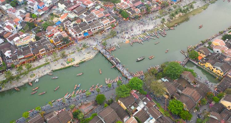 Vista aérea con dron del Pueblo Antiguo de Hoi An a lo largo de ambos lados del río lleno de botes y peatones