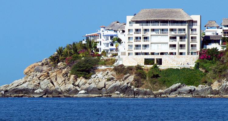 Gebäude eines Küstenresorts auf einem felsigen Vorgebirge mit Blick auf das ruhige blaue Meer