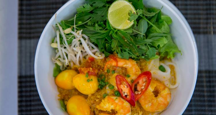 Tazón de primer plano de fideos con camarones, huevos de codorniz, chile y hierbas frescas.