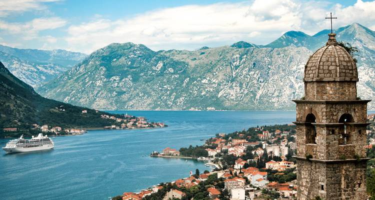 Mirador escénico de la bahía de Kotor con campanario de piedra en primer plano y crucero debajo de picos escarpados
